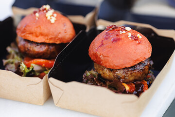 Chef packs street food for delivery in foil, burgers with wooden skewer