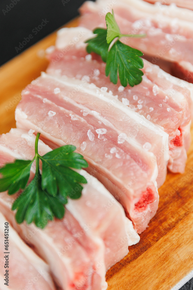 Wall mural Fresh meat pork ribs with green on wooden board, top view on dark background