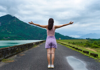 Young russian woman traveler with opened arms near lake and mountains in Khanh Hoa Province, Vietnam