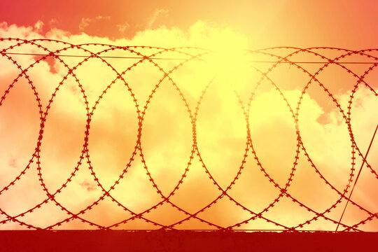 the red sky from the explosion behind the barbed wire. The war in Ukraine