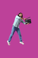 Jumping man with movie clapper on magenta background