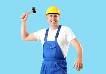 Mature worker with hammer on blue background. Labor Day celebration