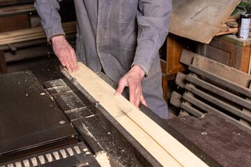 A craftsman works on woodworking machines and saws in a furniture workshop