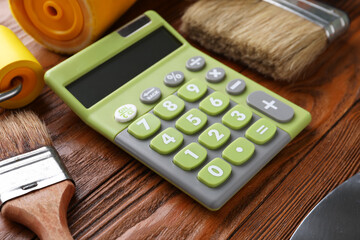 Calculator and painting tools on wooden background. Renovation budget concept
