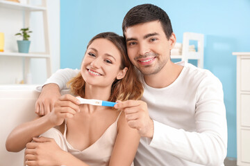 Happy young couple with positive pregnancy test in bathroom