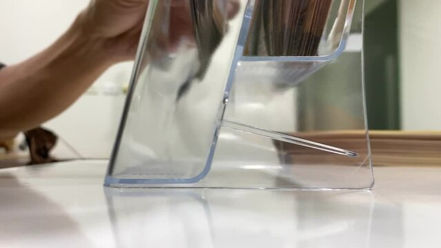 Close up brochure stand on table inside office. Male hand worker putting brochures in plastic container