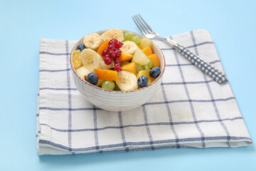 Bowl with fresh fruit salad on blue background