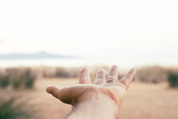 Pov of man hand against a moody scenic destination travel background with bright clear sky and...