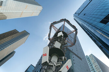 w angle view of 5g transmitter tower and modern office buildings.