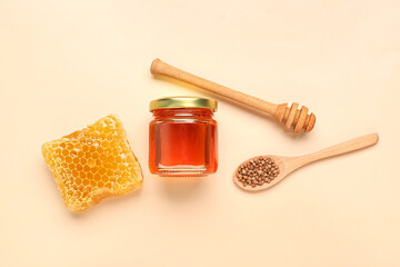 Jar with tasty honey, honeycomb, dipper and raw buckwheat on beige background