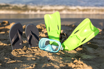 Stylish female flip flops, flippers and snorkeling mask on sand © Pixel-Shot
