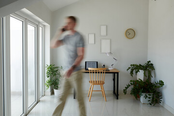 Blurred motion of man talking on phone when walking in his home office