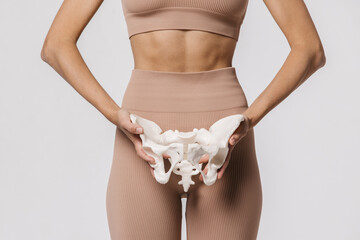 Close-up of the female pelvis in the hands of an athletic, healthy woman. Gynecology, women's healthcare and medicine and healthy body concept. - obrazy, fototapety, plakaty