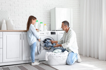 Mature man with his little granddaughter doing laundry at home - obrazy, fototapety, plakaty