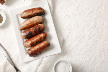 Plate of tasty grilled sausages on white background