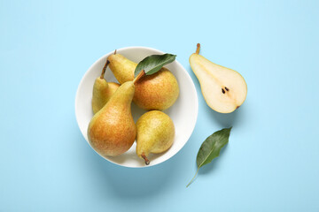 Bowl with ripe pears on blue background