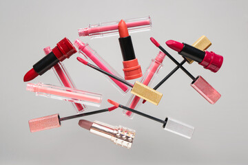 Different lipsticks flying on grey background