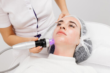 A young woman undergoes a fractional radiofrequency needle procedure for a face lift at a beauty clinic. Beauty and cosmetology concept.