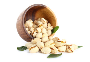 Wooden bowl with tasty pistachio nuts and leaves on white background