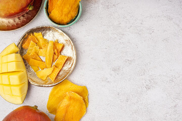Plate and bowl with slices of dried mango on white background