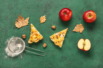 Pieces of delicious apple pie and ingredients on green background