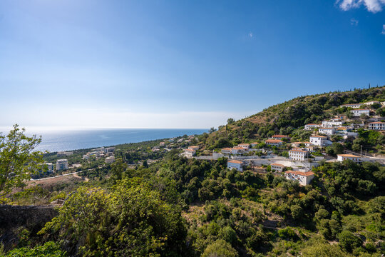 View of white houses with yellow shutters, moutains and sea. Vuno, Albania.