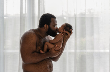 Young black dad no shirt with carrying and kissing his cute little son baby with love and happiness...