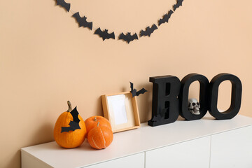 Halloween pumpkins with frame and word BOO on commode in room