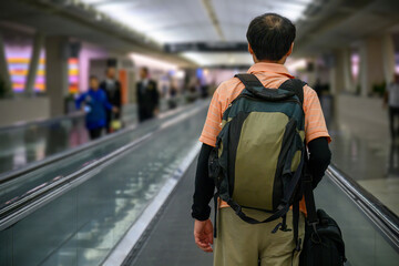 Man walking on the moving walkway at an airport. Unrecognisable people in the background.
