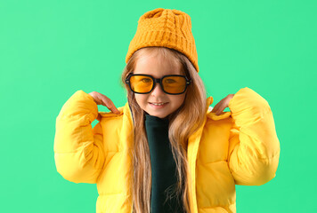 Cute little girl in puffer jacket on green background, closeup