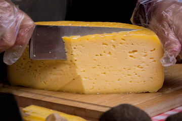 hand with knife cutting a cheese on the wooden board. Dairy product. Healthy eating and lifestyle.