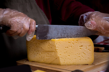 hand with knife cutting a cheese on the wooden board. Dairy product. Healthy eating and lifestyle.