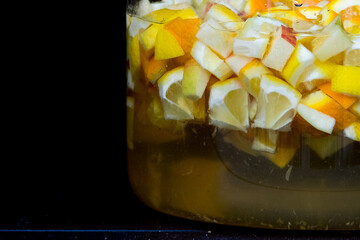 Lemonade in a glass jar with lemon slices on a dark background, front view