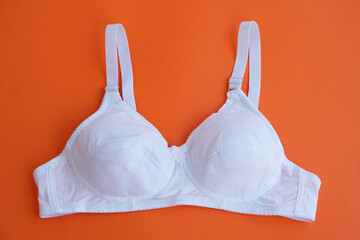White bra on orange background. Concept, feminine brassiere. Classic comfortable with cup A for...