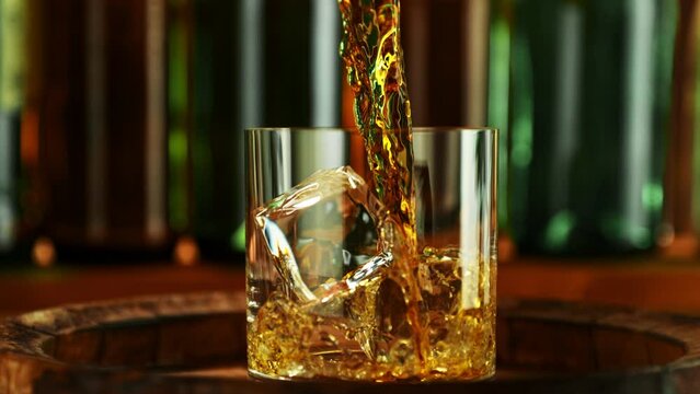 Super Slow Motion of Pouring Whisky from Bottle. Filmed on High Speed Cinema Camera, 1000 fps, Placed on High Speed Cine Bot. Camera Follows the Stream of Liquid. Speed Ramp Effect.