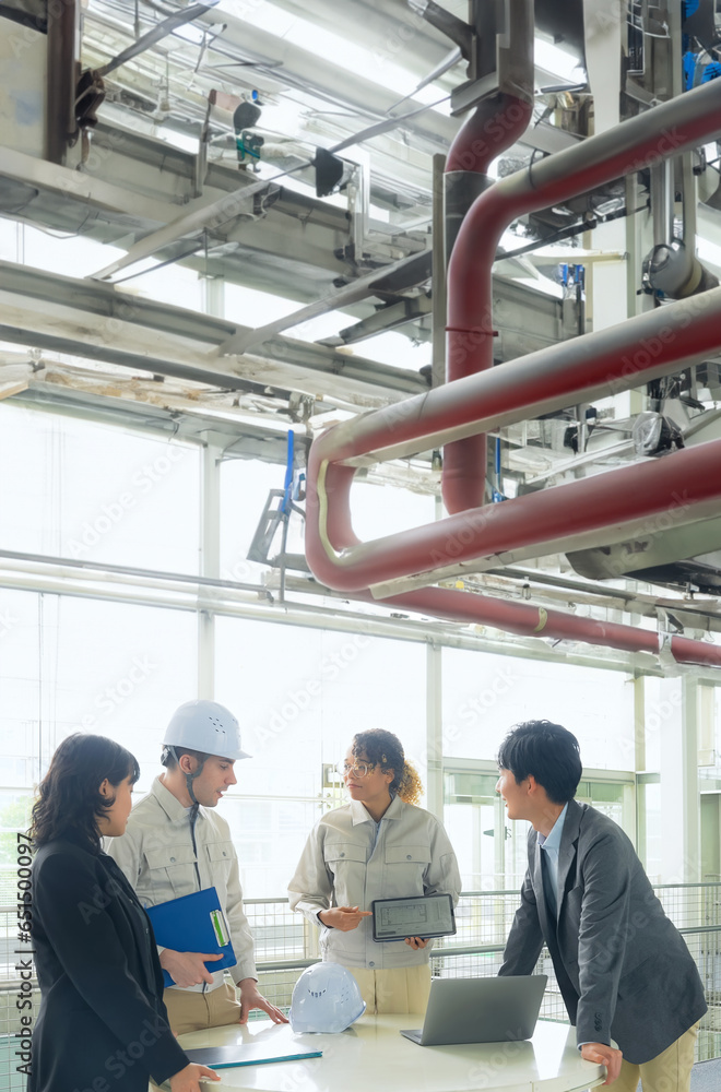Poster a group of multinational engineers meeting under the factory pipes.