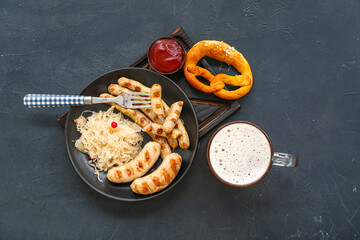 Bowl with tasty Bavarian sausages, sauerkraut, pretzel and mug of beer on black background. Oktoberfest celebration
