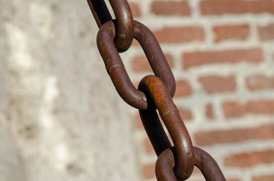 rusty chains, brick background, a symbol of strength and oppression, used in industry in crowbars as well as for slavery. very large chain links.