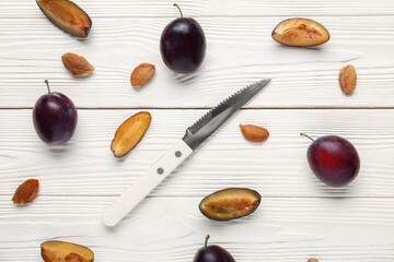 Fresh ripe plums on white wooden background