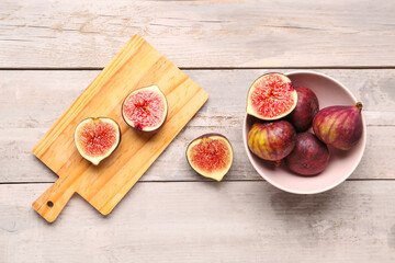 Bowl and board with fresh ripe figs on grey wooden background