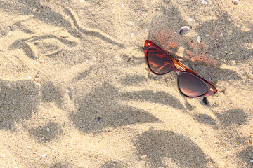 Fototapeta na wymiar Stylish brown sunglasses on sand