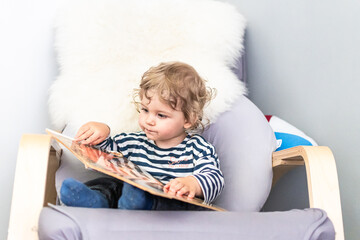 Baby liest Buch auf einem Schaukelstuhl - obrazy, fototapety, plakaty