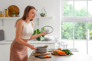 Young woman cooking chicken soup in kitchen