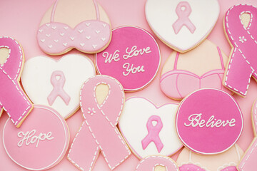 Cookies with ribbons and supportive words on pink background. Breast cancer awareness concept - obrazy, fototapety, plakaty