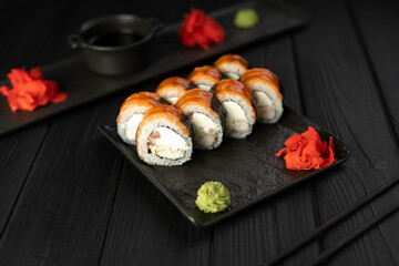 Sushi rolls with salmon, perch, cucumber and cream cheese on a black plate on a dark background. Japanese cuisine concept