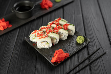 Sushi roll with caviar tobico, avocado and cream cheese on black background. Sushi menu. Japanese food concept.