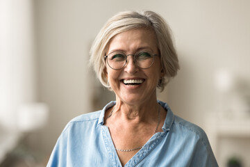 Cheerful pretty blonde older woman in elegant glasses looking at camera with beautiful toothy...