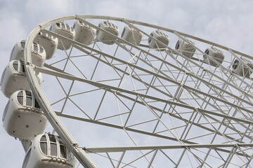 Modern white Ferris wheel in the central park against sky. Entertainment, attraction, amusement park. 