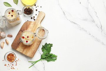 Jars with delicious sauerkraut and different spices on white background