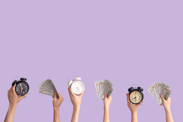 Hands holding different alarm clocks and money on lilac background